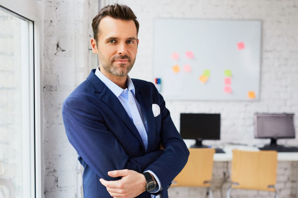 A male growth marketing manager standing in office and looking at the camera.